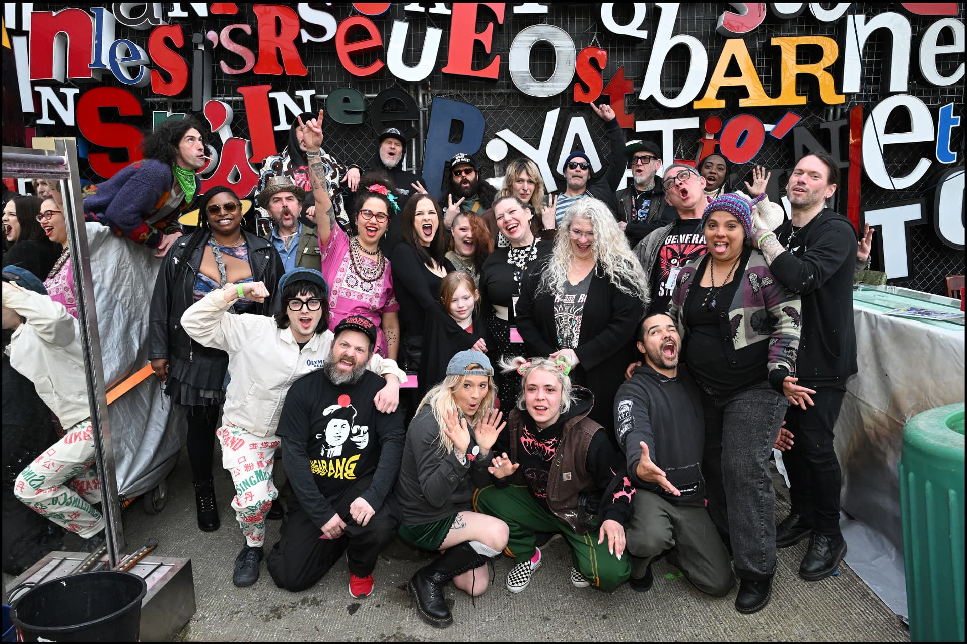Punk Rock Flea Market vendors posing together in front of the salvaged letter wall