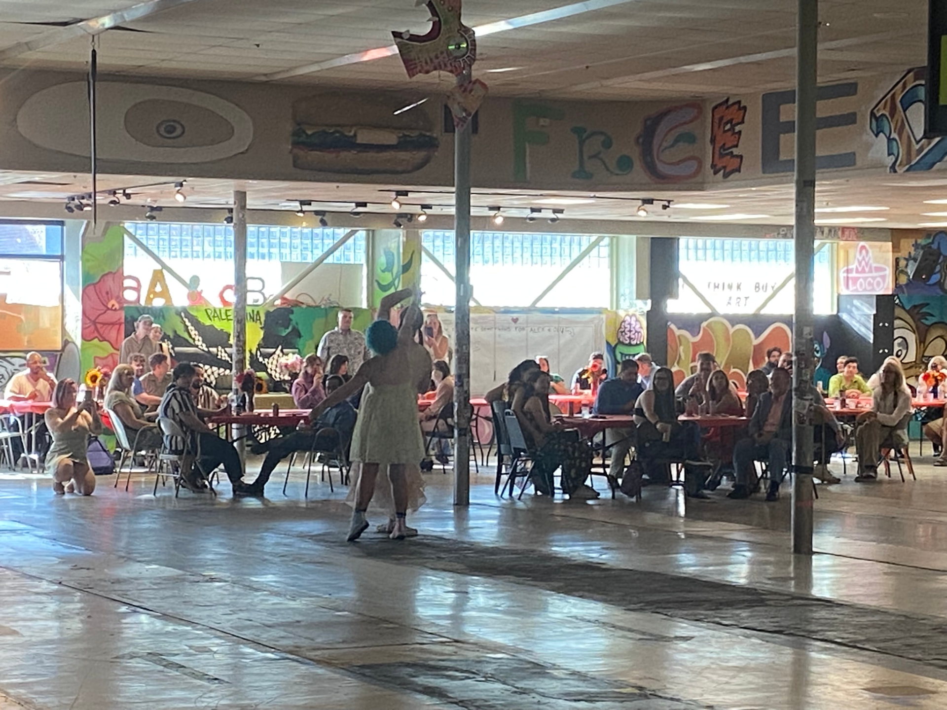 A performer on the open floor in front of seated guests at the Quality Flea Center